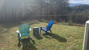 An outdoor seating area with two chairs and a small table, surrounded by a chain-link fence and trees. - Private Basement Room Pet Friendly Fenced Yard (Copperhill)