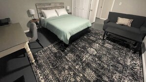 A bedroom with a bed, a desk, a couch, and a patterned rug. - Private Basement Room Pet Friendly Fenced Yard (Copperhill)