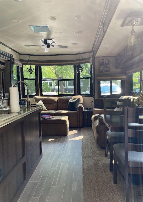 Interior espacioso de una autocaravana con zona de cocina, asientos y grandes ventanales con vistas al exterior.