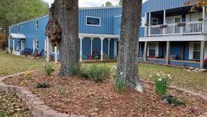 Un immeuble bleu à deux étages, doté d’un balcon, entouré d’arbres et agrémenté d’un jardin paysager.