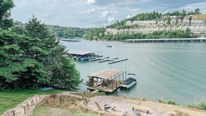 Une vue sur le lac, avec un quai, une petite construction en bois et une rangée de bâtiments en arrière-plan.