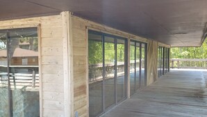 A covered wooden deck with glass doors leading to an outdoor area. - Portside townhouse with beach access and pools (Panama City Beach)