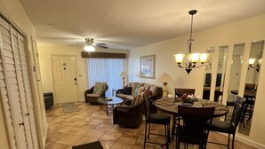 A spacious living room with a dining area, a large mirror, and a ceiling fan. - Portside townhouse with beach access and pools (Panama City Beach)