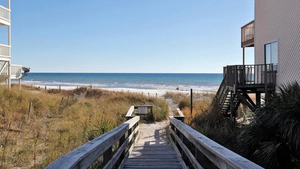 A wooden boardwalk leading to a beach with a clear view of the ocean. - Portside townhouse with beach access and pools (Panama City Beach)