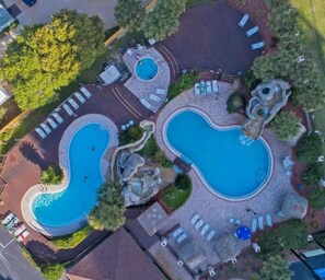Vue aérienne d’un complexe hôtelier doté de deux piscines, d’espaces de détente et de jardins aménagés.