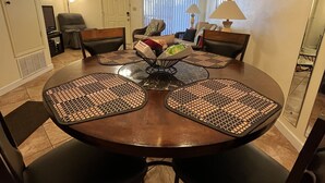 A dining area with a round table, black chairs with patterned mats, a chandelier, and a television in the background. - Portside townhouse with beach access and pools (Panama City Beach)