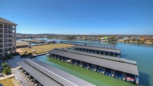 Een jachthaven met aangemeerde boten, een overdekte parkeerplaats en een groot gebouw met meerdere verdiepingen.