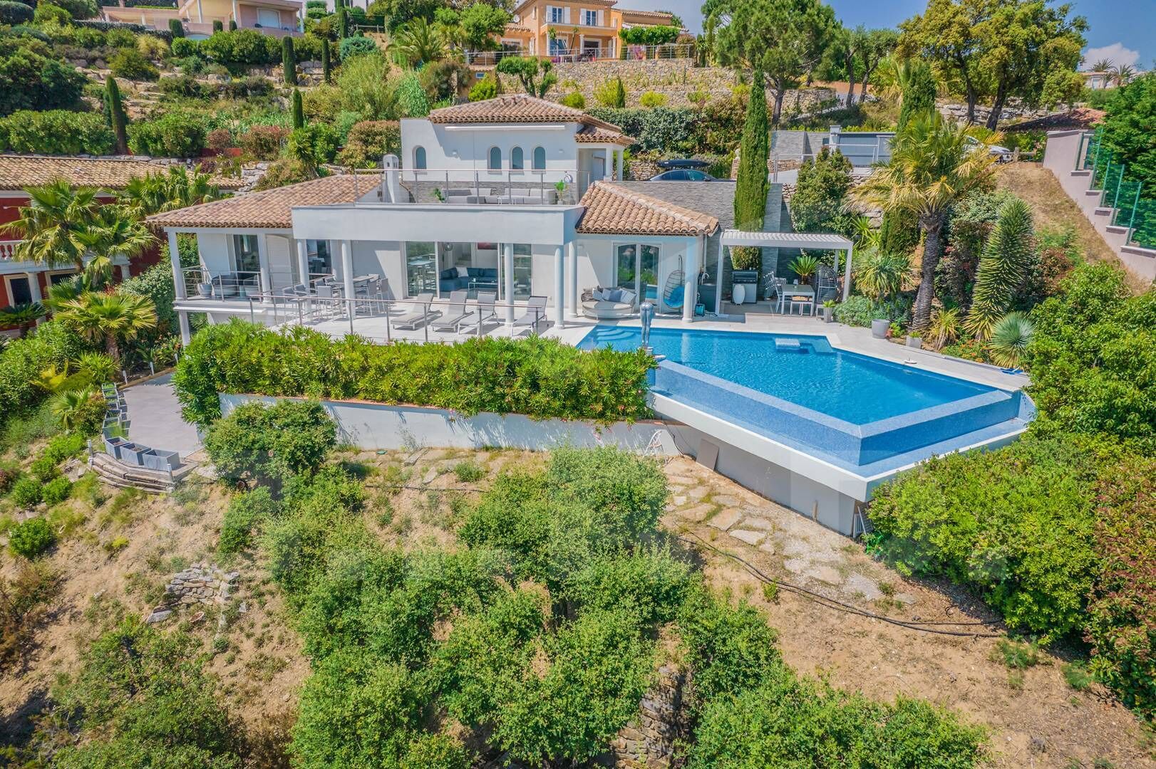 A large house with a swimming pool, surrounded by lush greenery and hills.