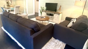A modern living room with a sectional sofa, a coffee table, and a flat-screen TV on a wooden stand.