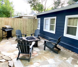 Een terras met stenen vloer, een barbecue en Adirondack-stoelen.