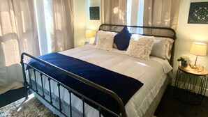 A bedroom with a bed, curtains, a nightstand, and a lamp.