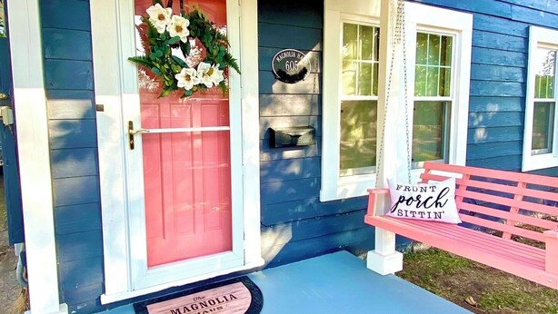 A porch with a red door, a bench, and a hanging light fixture.