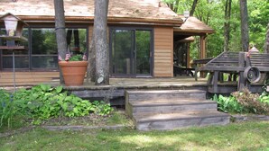 A wooden house with a porch, large windows, and a tree in front. - Nature lovers retreat right on the edge of the river (Hersey)