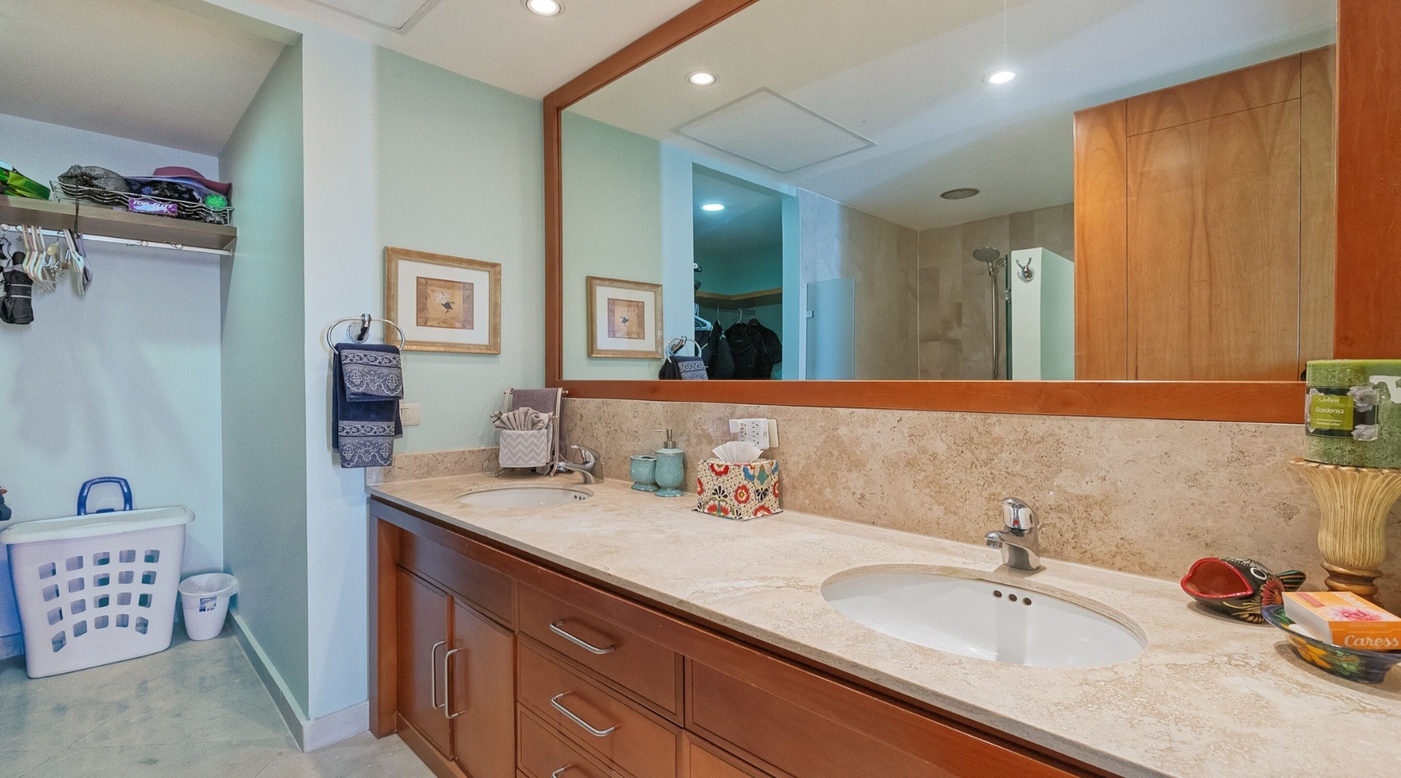 A bathroom with a large mirror, wooden cabinets, a sink, and a shower area.