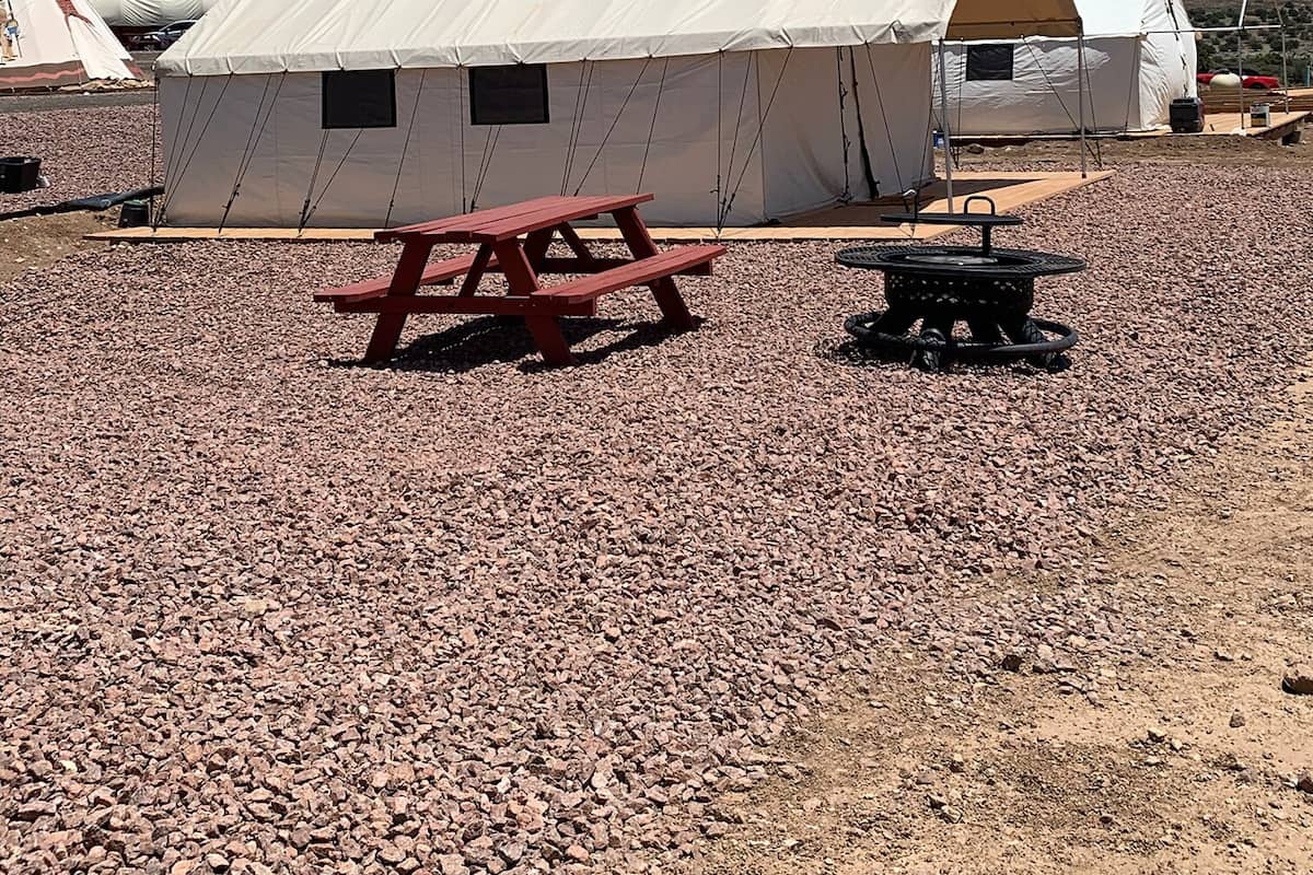 A tented camping area with a picnic table and a fire pit.