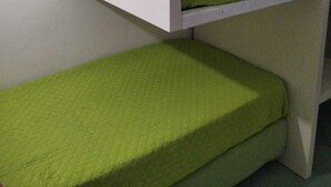 Una cama litera con ropa de cama verde y una pared blanca.