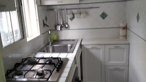 Una cocina con armarios blancos, una estufa a gas y un fregadero.