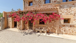 A stone building with a bench and pink flowers in front.