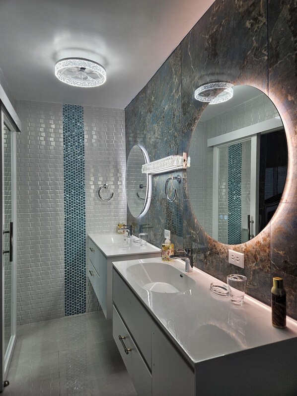 Un baño moderno con dos lavamanos, un espejo grande y un diseño único de baldosas hexagonales en la pared.