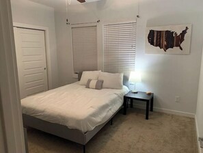 Relax in a serene bedroom with a comfortable bed, bedside table, and a unique map artwork.