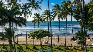 A beach with palm trees, a sandy shore, and lounge chairs. - Ocean-View Condo / Lagoon Pool & Swim-Up Bar (Tamarindo)