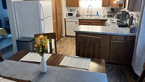 Une cuisine moderne avec des meubles en bois, un réfrigérateur blanc, un four à micro-ondes et une machine à café.