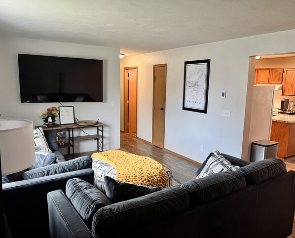 Ein modernes Wohnzimmer mit einem schwarzen Ledersofa, einer gelben Decke und einem flachbildfernseher an der Wand.