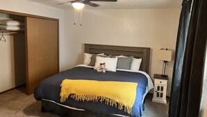 Une chambre à coucher comprenant un lit, un ventilateur de plafond, une table de chevet et une armoire.