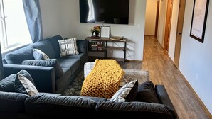 Un salon avec un canapé, une table basse et un téléviseur fixé au mur.