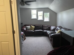 A corner living room with a brown leather sofa, a small table, and a window. - Cozy family home near Canfield Mountain with hot tub (Coeur d'Alene)