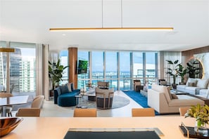 Enjoy a panoramic city view from the comfort of this stylish living room with a central seating area and dining space.