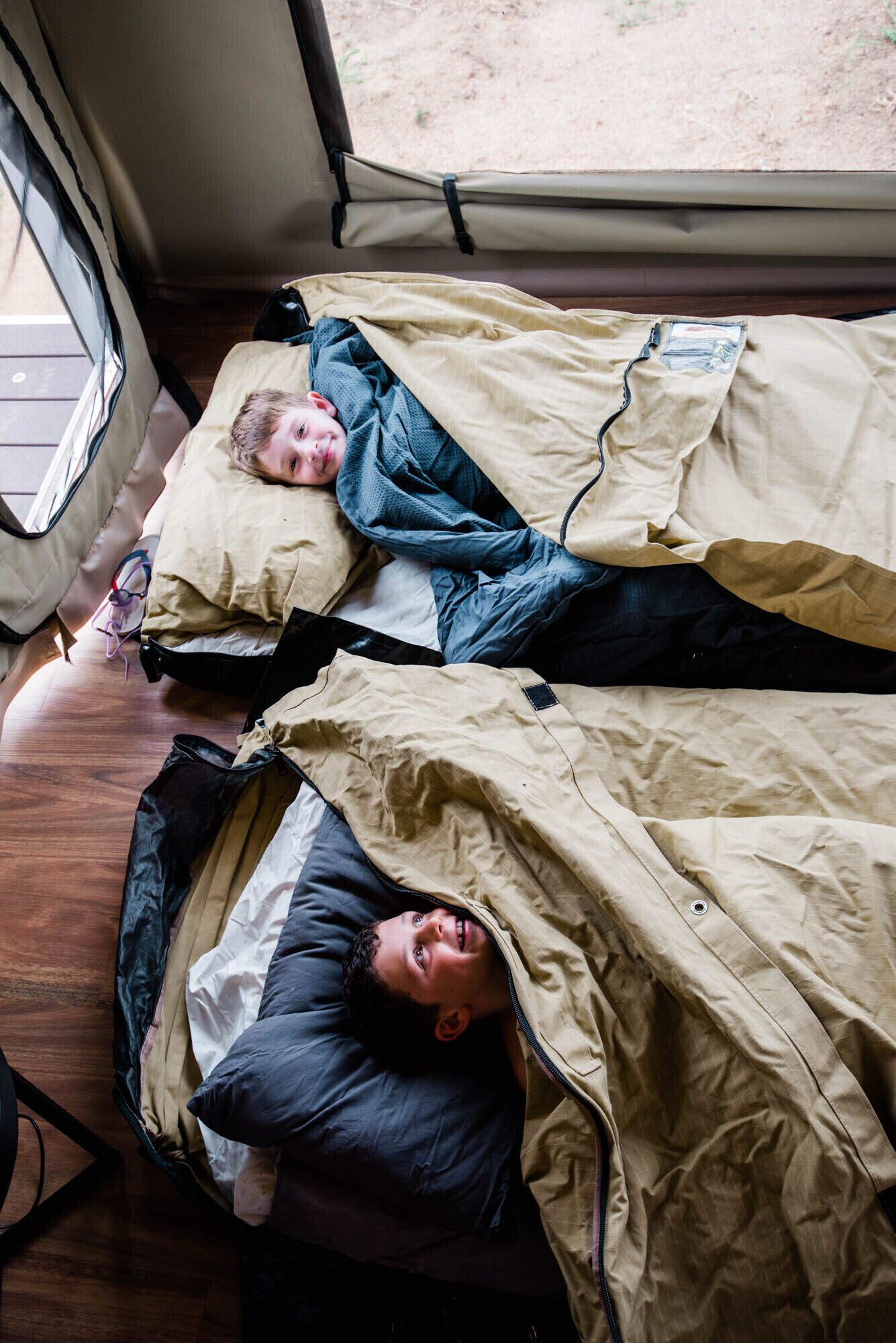 Two bunk beds with a window above, a wooden floor, and a visible door.