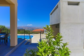 Una terraza con piscina, mobiliario exterior y vistas a colinas distantes.