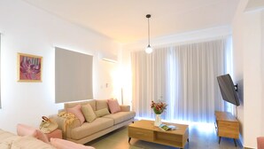 A modern living room with a beige sofa, a wooden coffee table, and a television on a wooden stand. - Villa Aeria: Holiday Villa To Rent, Pool, Views, WiFi, A/C (Meladeia)