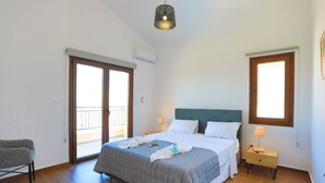 A bedroom with a bed, a nightstand, a chair, and a window. - Villa Aeria: Holiday Villa To Rent, Pool, Views, WiFi, A/C (Meladeia)
