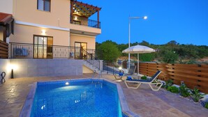 Ein modernes, zweistöckiges Gebäude mit Pool, Außenbereich und Blick auf die umliegende Landschaft.