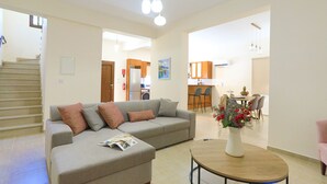 Ein geräumiges Wohnzimmer mit einer Couch, einem Couchtisch und einem Essbereich im Hintergrund.