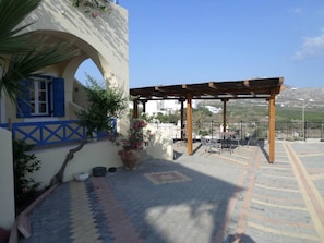 A patio area with outdoor seating, a pergola, and a view of the surrounding landscape.