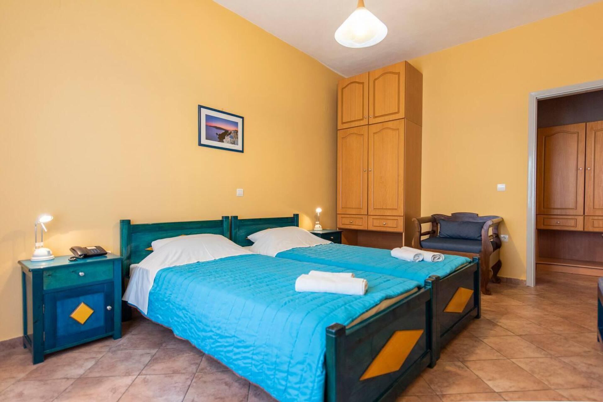 Ein Schlafzimmer mit einem Bett, zwei Nachttischen, einem Sessel und Holzschränken.