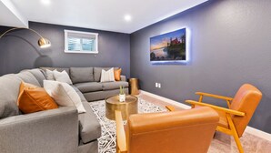 A modern living room with a gray sofa, a coffee table, and a tan armchair. - Modern Family Oasis ~ 5★ Location, Games, Backyard (Arvada)