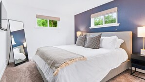 A bedroom with a bed, bedside tables, a mirror, and two windows. - Modern Family Oasis ~ 5★ Location, Games, Backyard (Arvada)