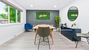 A modern meeting room with a large table, chairs, a dark-colored reception desk, and a green wall with 'Holland House' signage. - Modern Family Oasis ~ 5★ Location, Games, Backyard (Arvada)