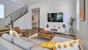 A modern living room with a staircase, a flat-screen TV, and a coffee table. - Mid-Century Modern Palm Springs Home w/ Pool (Palm Springs)