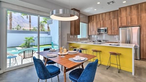 A modern kitchen with wooden cabinets, a stainless steel refrigerator, and a yellow island counter. - Mid-Century Modern Palm Springs Home w/ Pool (Palm Springs)