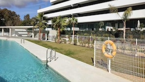 A modern building with a swimming pool, palm trees, and a lifebuoy on a fence. - Modern one  km from the centre and La Rada Beach. (Estepona)