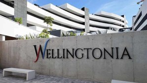 A concrete wall with the word "Wellingtonia" in large letters, a white bench, and a modern building in the background. - Modern one  km from the centre and La Rada Beach. (Estepona)