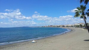 A beach with a clear sky, calm sea, and a row of buildings along the shore. - Modern one  km from the centre and La Rada Beach. (Estepona)