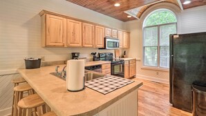 Una cocina con armarios de madera, microondas, estufa y refrigerador.