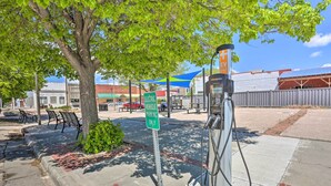A parking area with electric vehicle charging stations, a tree, and a sign indicating electric vehicle parking only. - Peaceful Chadron Apartment in Historic Hotel! (Chadron)