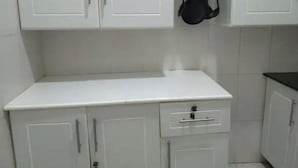 A kitchen with white cabinets, a countertop, and hanging utensils. - Pretty Kigali studio. (Kigali)